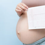 Das Bild zeigt eine hochschwangere Frau zusammen mit einem CTG-Streifen.