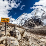 Auf diesem Bild ist der steinige Weg zum Mount Everest Basecamp erkennbar. Ein Wegweiser zeigt in die richtige Richtung.